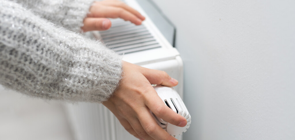 The child's hands warm their hands near the heating radiator. Saving gas in the heating season